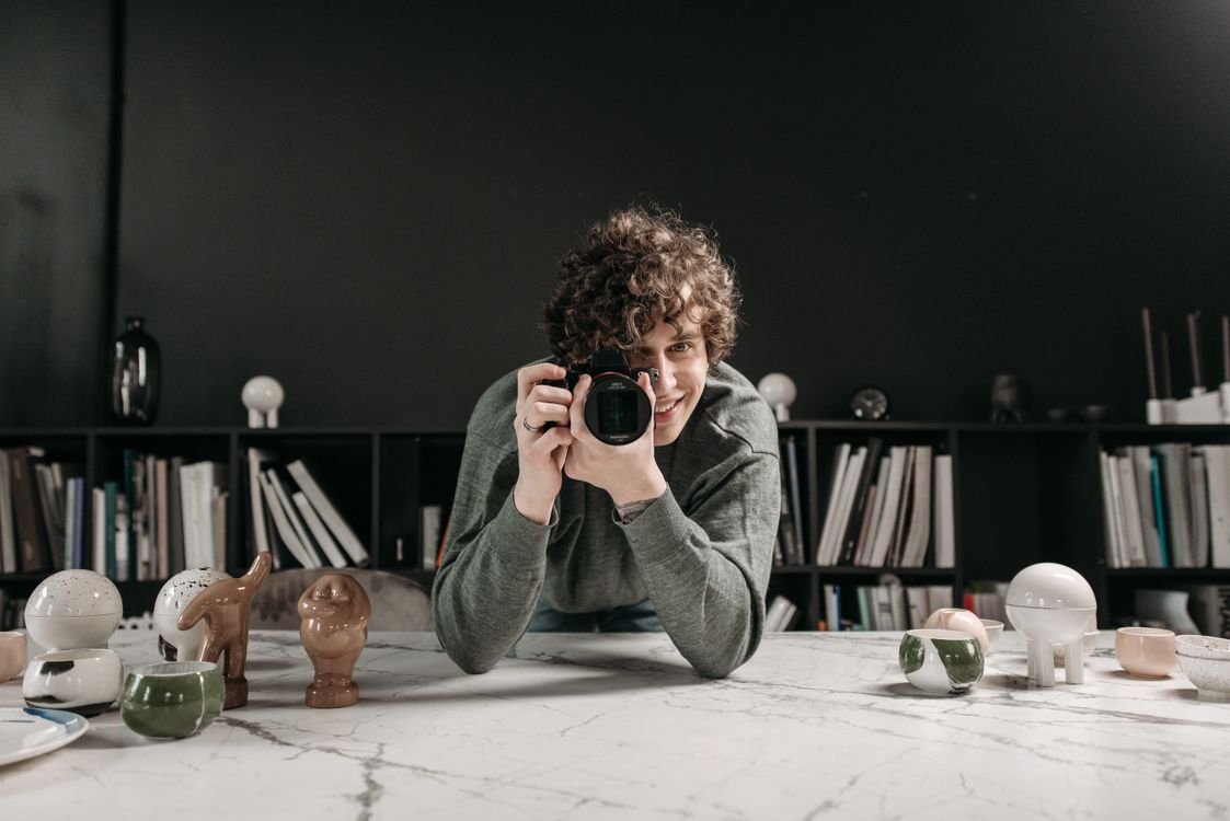 Photographer shooting products on a marble table in a studio with softbox lighting